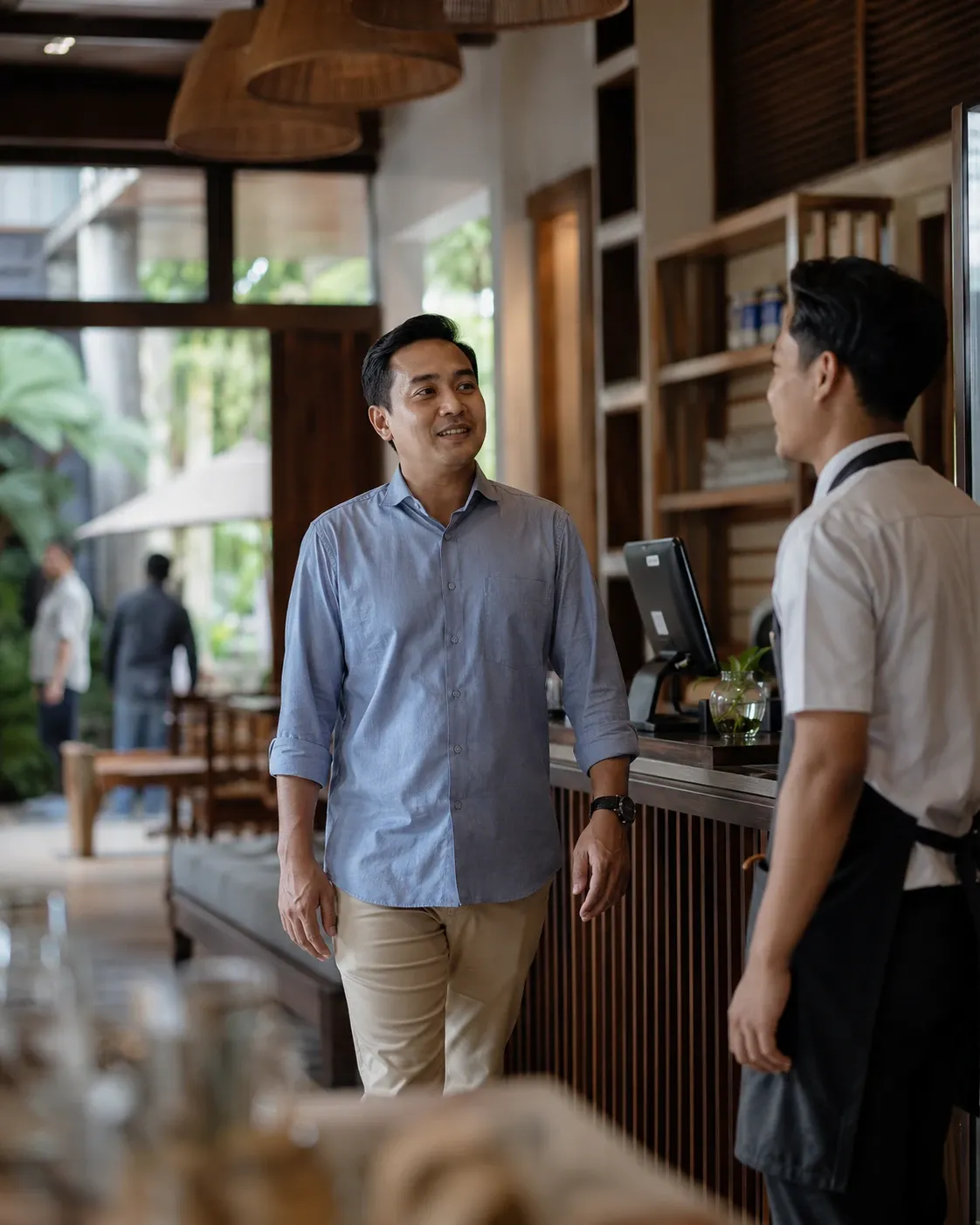 A business owner talking with staff at the counter of his café